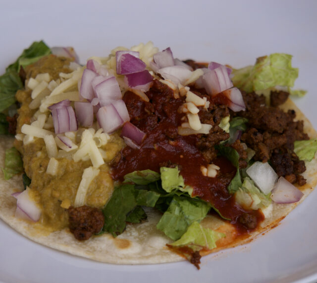 New limited time taco with seasoned ground beef, romaine, New Mexico red chile sauce, Hatch green chile sauce (spicy!), Monterey Jack cheese, red onion, flour tortilla.